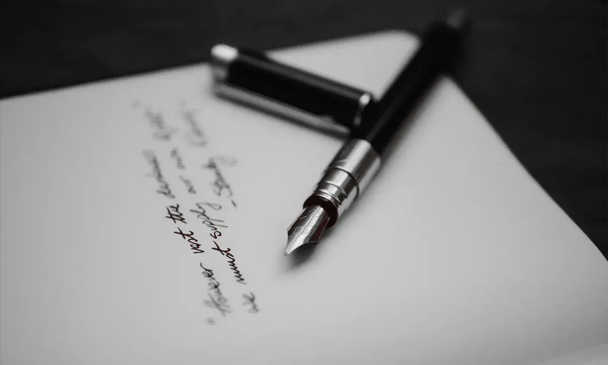 Pióro wieczne na papierze, gdzie widnieje fragment tekstu, być może ostatnia wola lub testament.