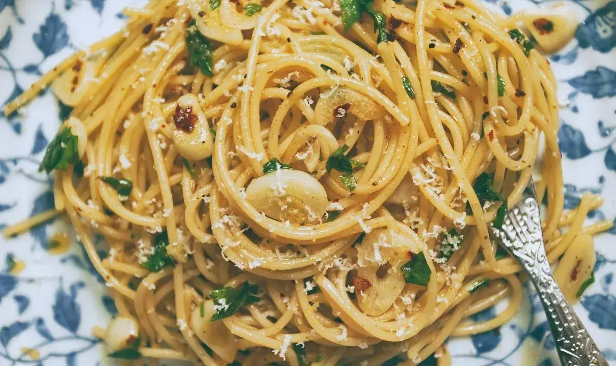 Pyszne spaghetti aglio olio z czosnkiem, natką pietruszki i płatkami chili, posypane parmezanem.