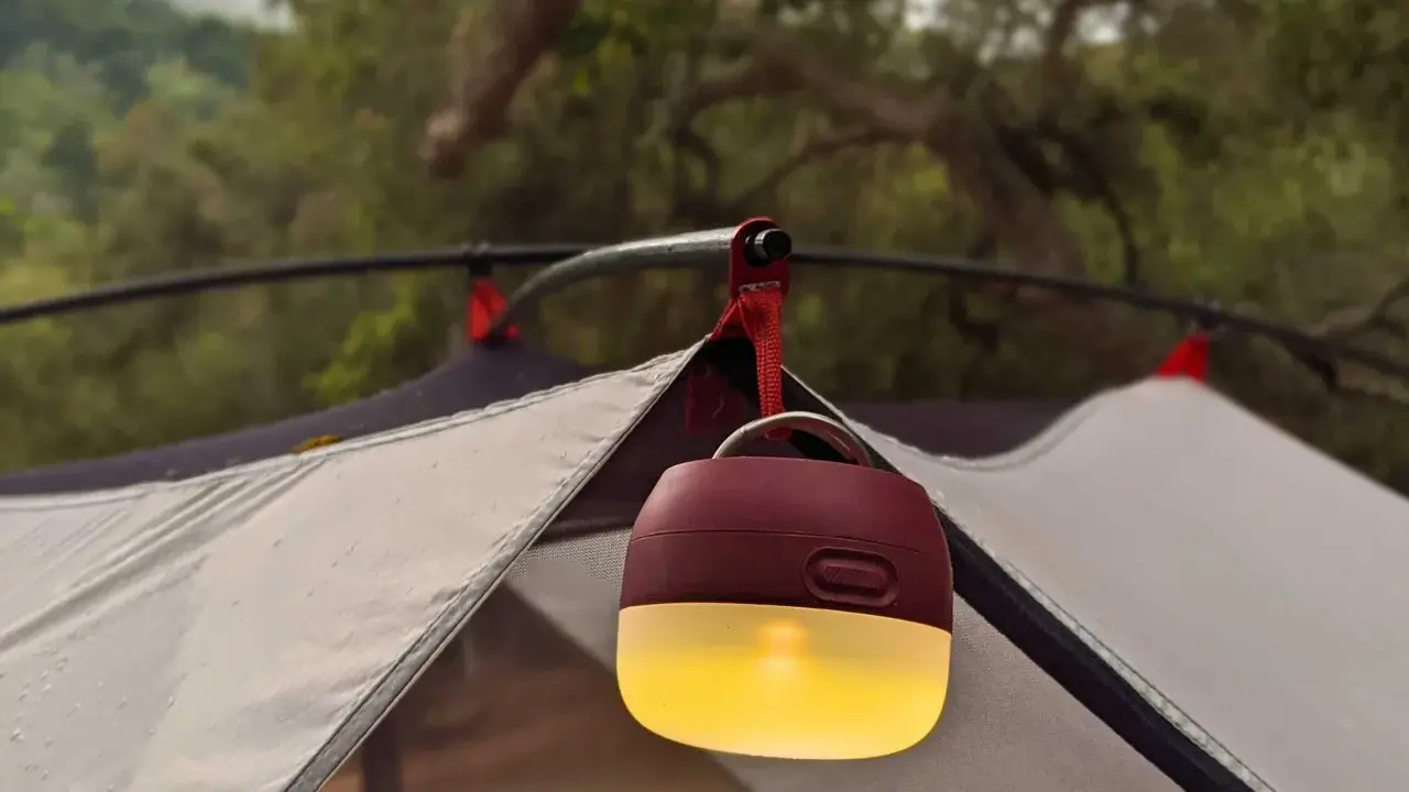 En mysig campingbelysning hänger från tältstången och lyser upp kvällen.