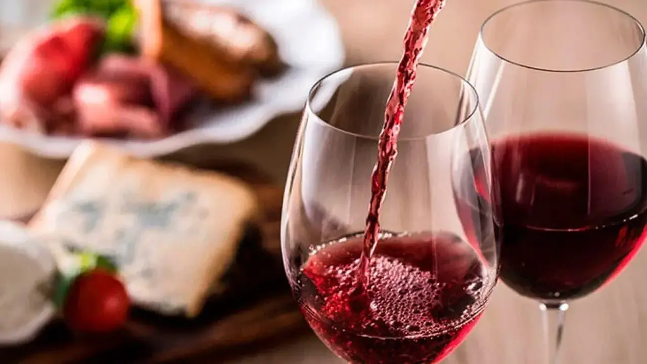 Vino tinto servido en copas, con tabla de quesos y embutidos al fondo. Una cata para apreciar la diferencia entre tempranillo y crianza.