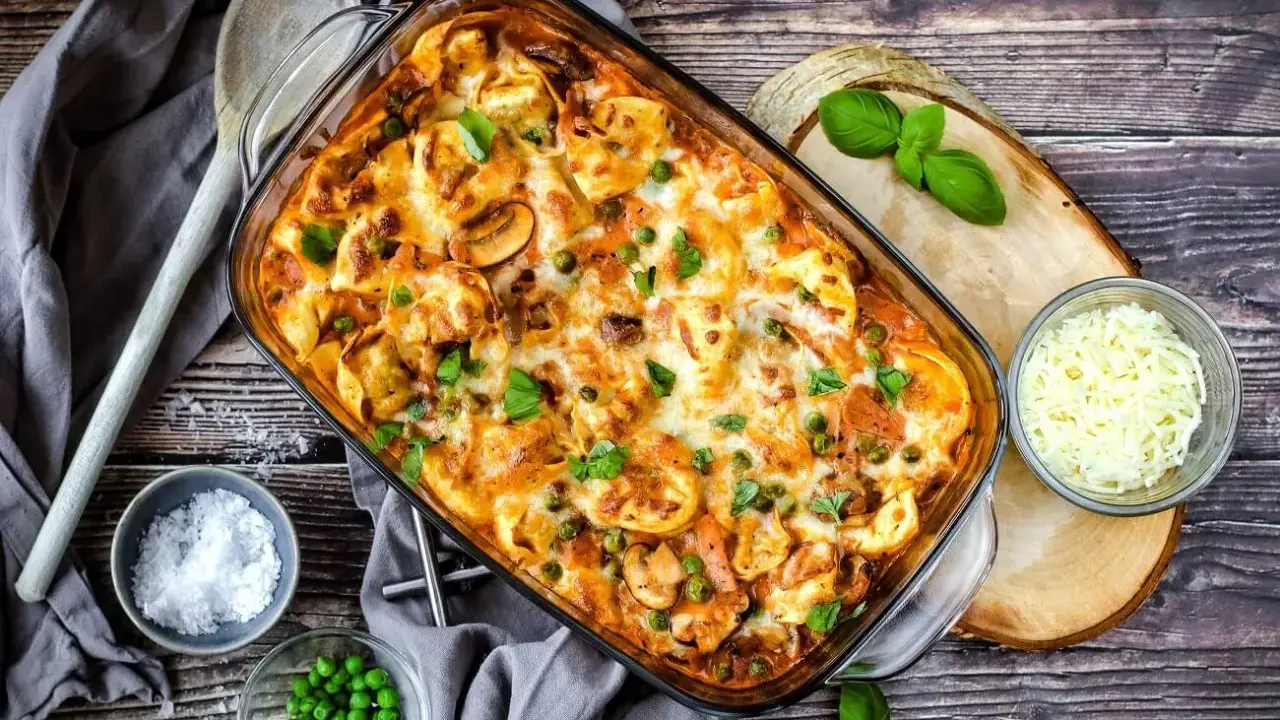 Herzhafter Tortellini Auflauf mit Erbsen und Pilzen, überbacken mit Käse und garniert mit frischem Basilikum.