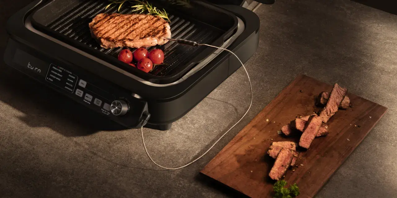 Idealne grillowanie na grillu elektrycznym. Soczysty stek z pomidorkami i rozmarynem, a obok pokrojone mięso na desce.