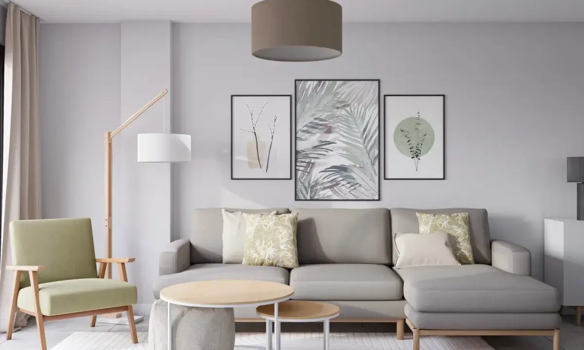 Salón moderno con sofá gris, sillón verde y tres cuadros con motivos botánicos, mostrando diferentes formas de poner cuadros en la pared.