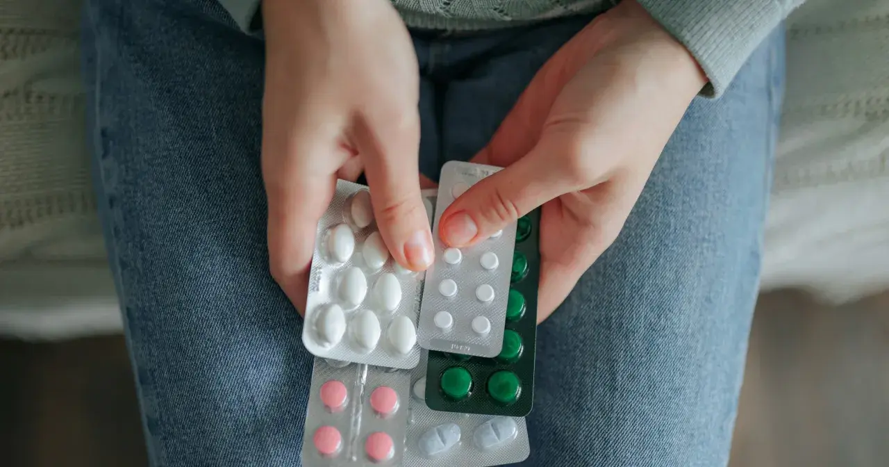 Dłonie trzymają opakowania tabletek. Statyny a seniorzy – troska o zdrowie serca w starszym wieku.