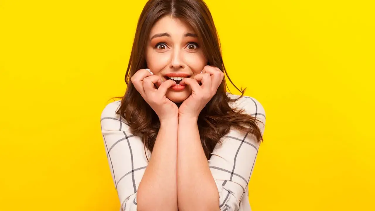 Ragazza con espressione preoccupata che si mangia le unghie, un chiaro segno di gestione dell'ansia.