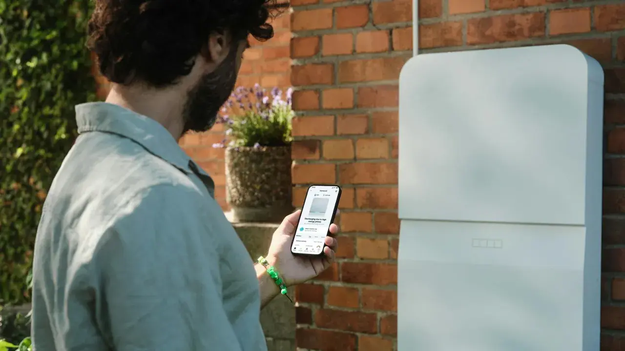 Man kollar sin mobil som visar information om sin batteribank hemma.