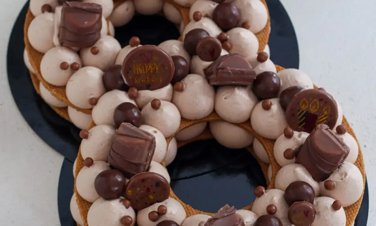 Gâteau number cake chocolat, décoré de crème onctueuse, de chocolats et de billes croquantes. Parfait pour une recette number cake chocolat d'anniversaire.