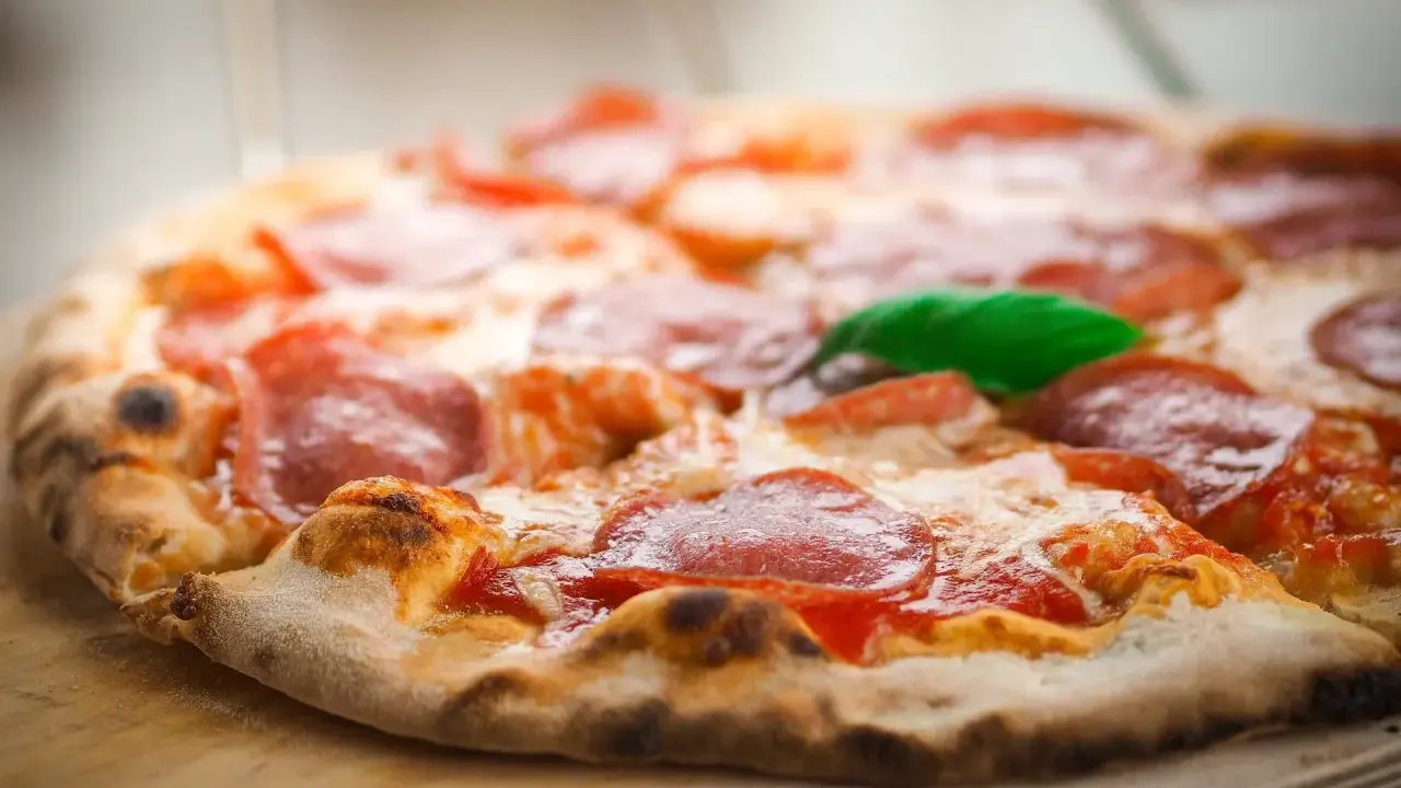 Eine köstliche italienische Pizzateig-Pizza mit Salami und Basilikum, frisch aus dem Ofen.