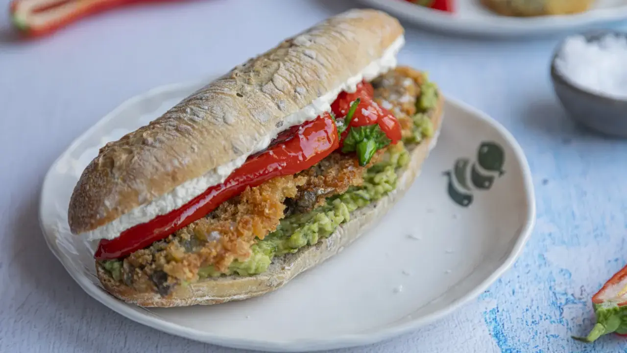 Pyszna kanapka ze śledziem, awokado i pieczoną papryką na chrupiącej bułce. Idealna na szybki lunch.