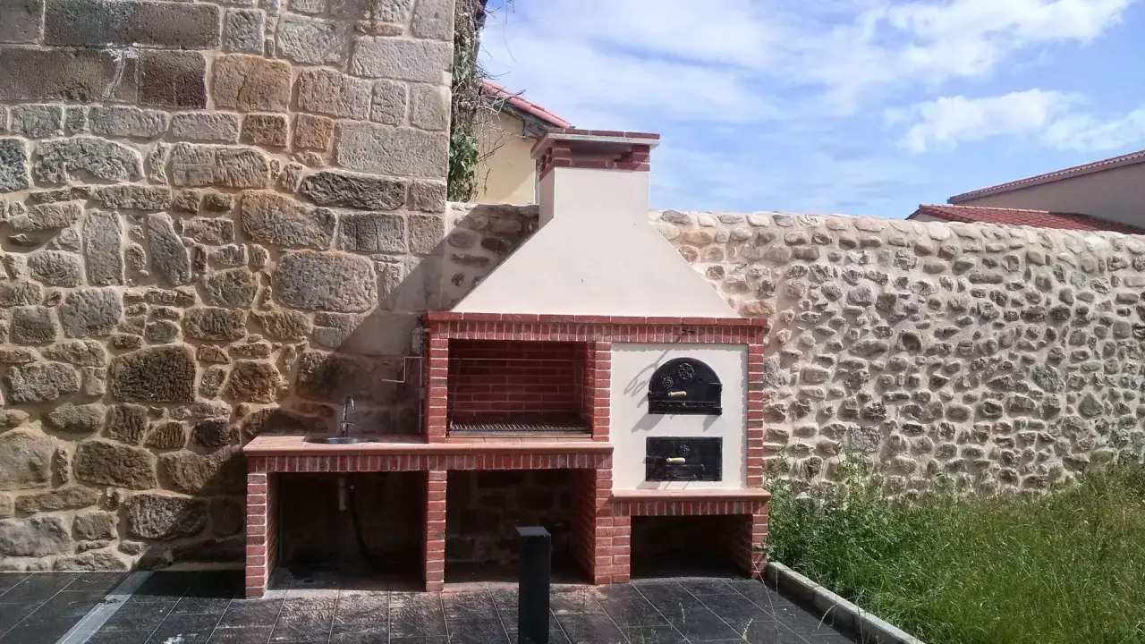 Barbacoa de obra con horno de leña y fregadero, lista para disfrutar de una comida al aire libre.