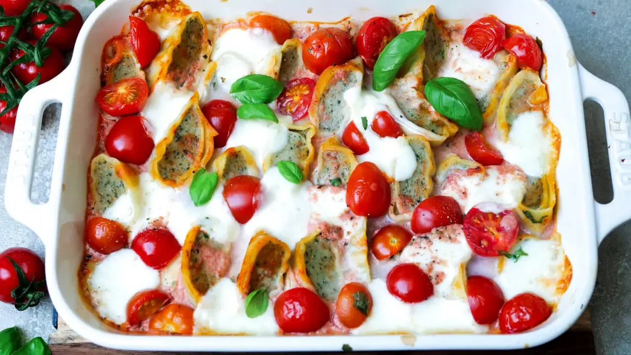 Herzhafter Maultaschen Auflauf mit Kirschtomaten und geschmolzenem Mozzarella, garniert mit frischem Basilikum.