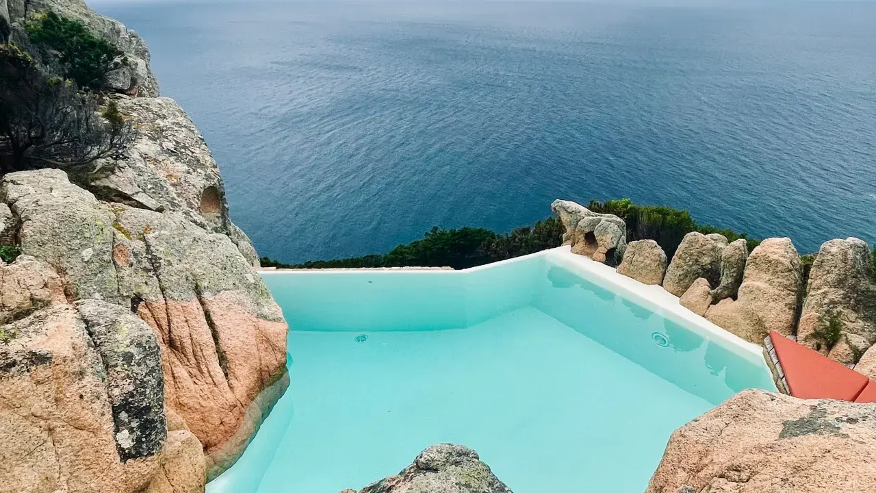 Piscina a sfioro incastonata tra rocce granitiche, con vista sul mare blu intenso. Un angolo di paradiso, forse un progetto di Alberto Ponis.