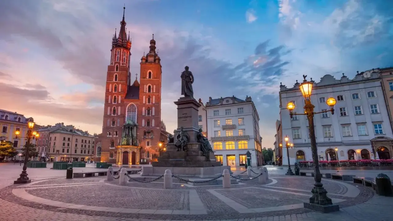 Kraków co warto zobaczyć: Rynek Główny z Kościołem Mariackim i pomnikiem Mickiewicza o zachodzie słońca.