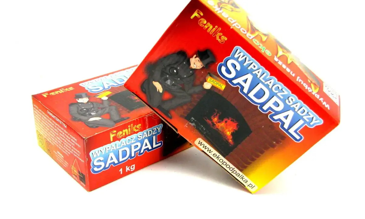 Dwa opakowania produktu "Wypalacz sadzy SADPAL" z kominiarzem na tle płonącego kominka.