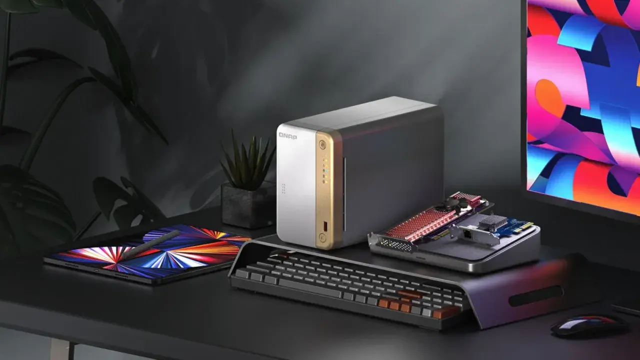 Un bureau moderne avec un NAS QNAP, une tablette, un clavier et un écran coloré. Idéal pour choisir son NAS et organiser ses données.