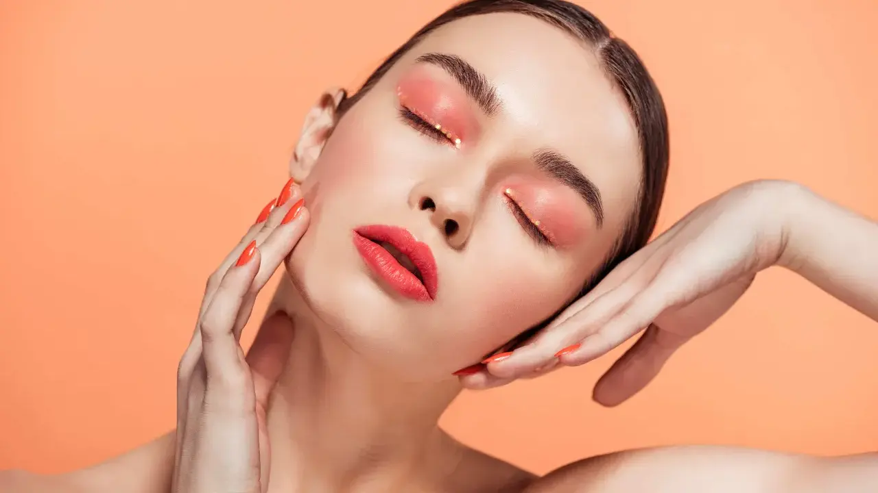 Maquillajes Euphoria: ojos con sombra coral brillante y labios rojos vibrantes, uñas a juego.