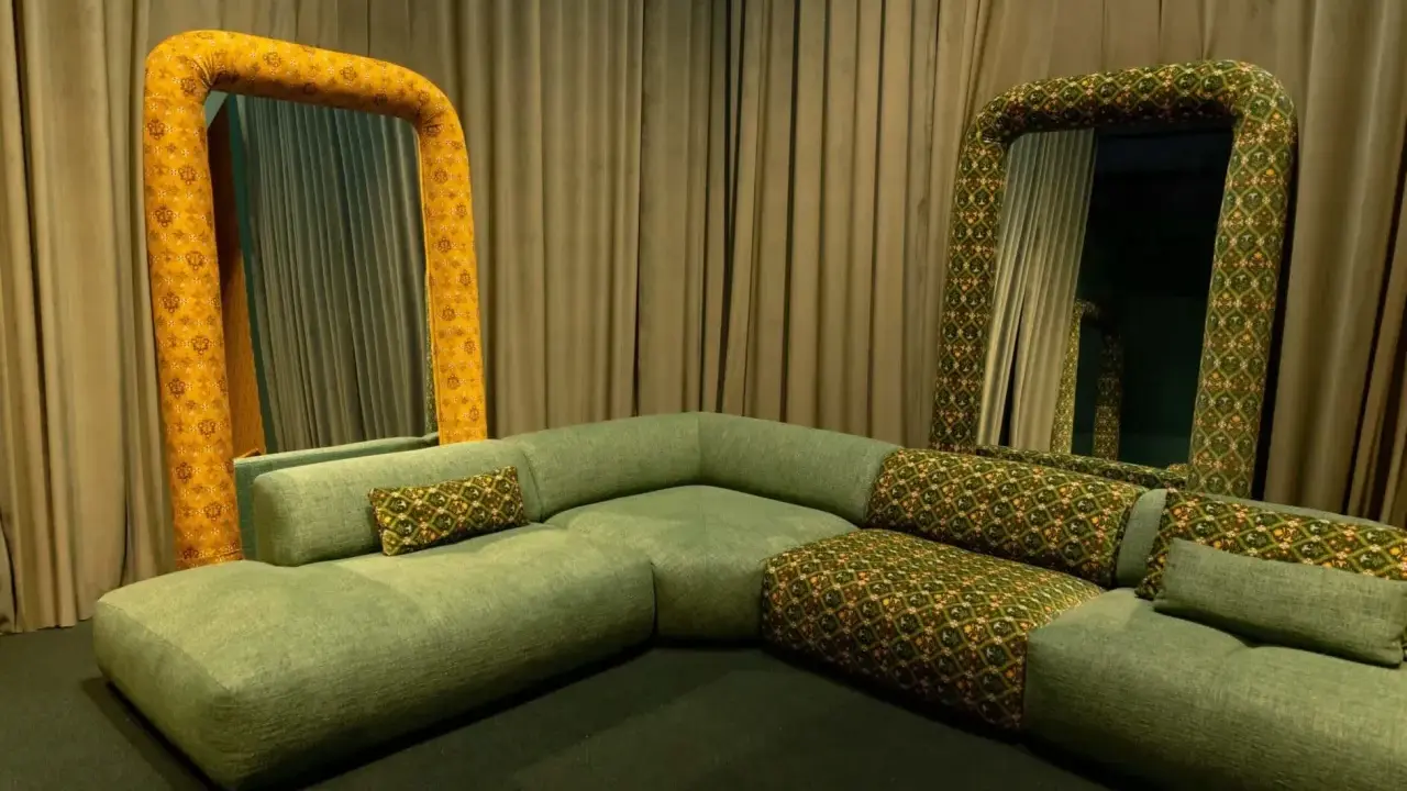 Salon w stylu vintage: zielona, modułowa kanapa i dwa lustra w ozdobnych, żółto-zielonych ramach.
