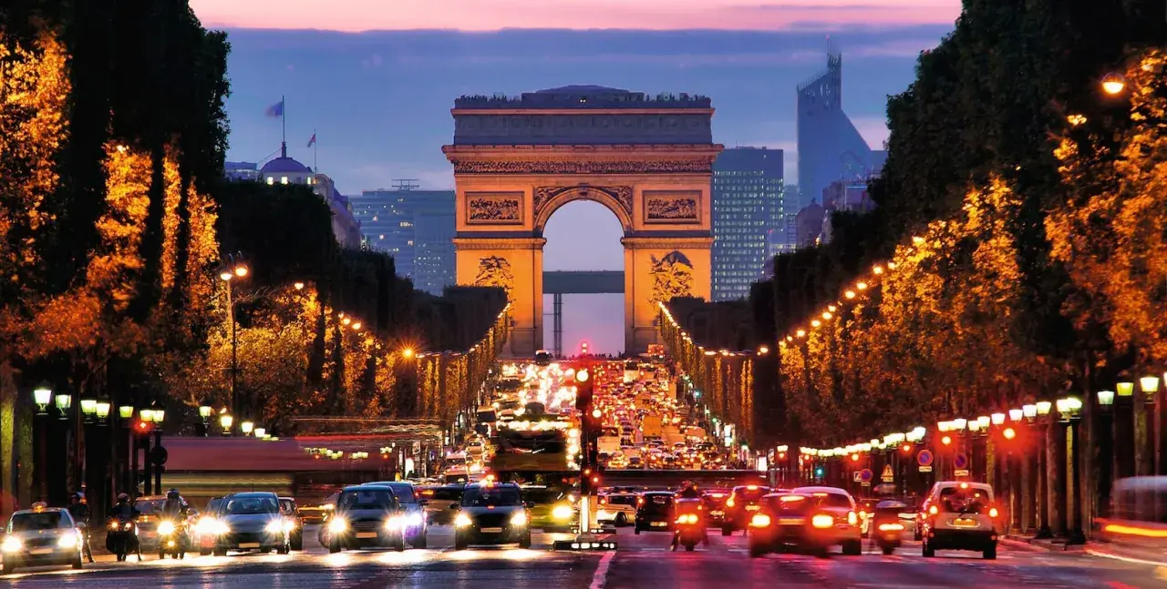 Trafikkaos vid Triumfbågen i Paris. En kvällspromenad här känns som att bada i Paris ljus.