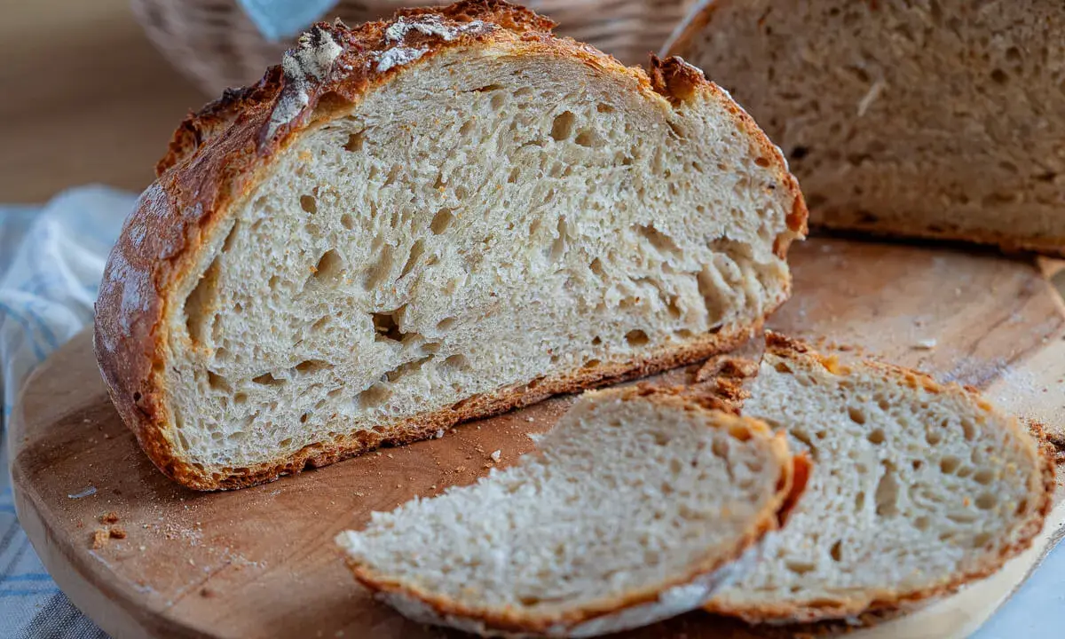 Frisches Brot ohne Sauerteig, mit knuspriger Kruste und luftiger Krume, liegt auf einem Holzbrett.