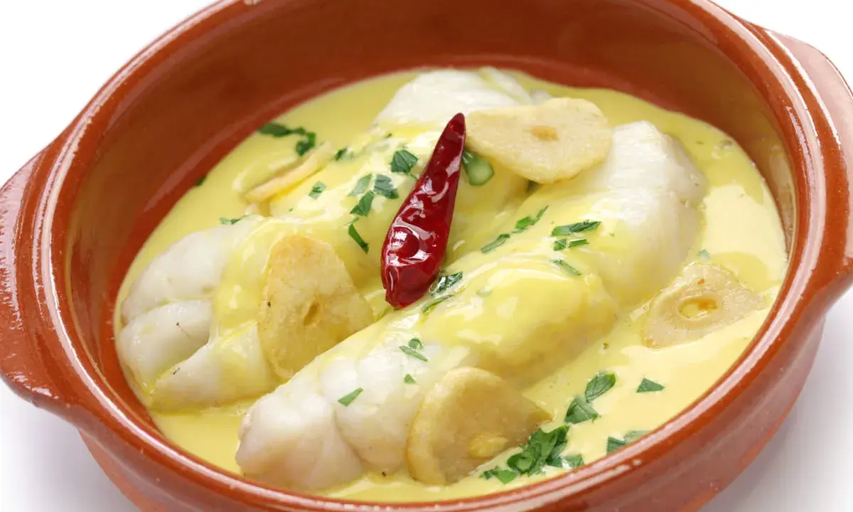 Bacalao al pil pil, uno de los platos típicos vascos, servido en cazuela de barro con ajo y guindilla.
