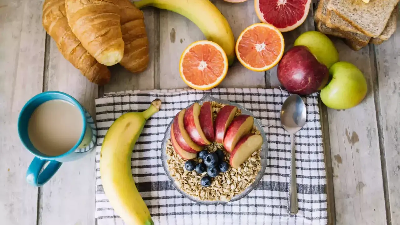 Pyszne i lekkostrawne śniadanie: owsianka z jabłkiem i jagodami, banan, croissanty, cytrusy i kawa.