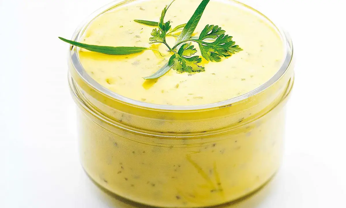 Sauce béarnaise onctueuse dans un bocal, garnie d'herbes fraîches. Parfaite pour accompagner vos plats, cette recette est un délice.