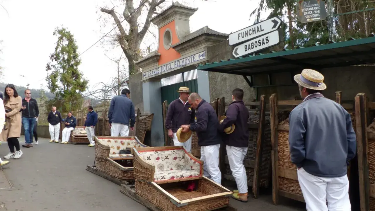 Korbschlitten Madeira: Männer in traditioneller Kleidung warten neben den Korbschlitten auf Fahrgäste.