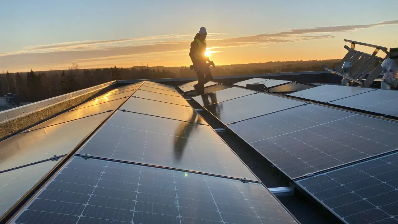 Arbetare installerar solpaneler på ett tak i solnedgången. Gosol Energi AB ser till att framtiden blir grön.