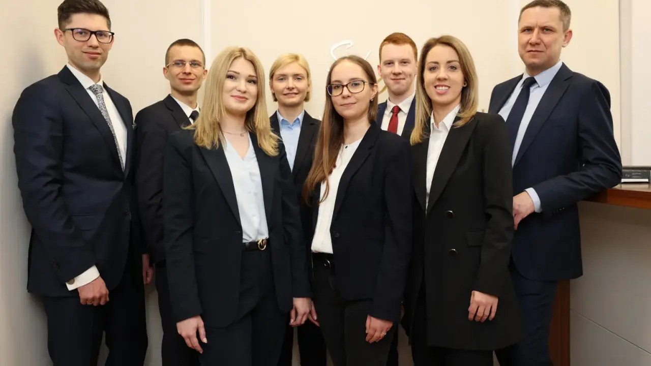 Grupa prawników w garniturach pozuje do zdjęcia.