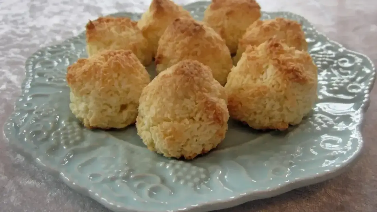 Små, gyllene kokostoppar på en vacker ljusblå tallrik. Perfekt för ett enkelt kokostoppar recept.