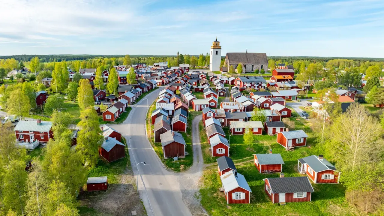 Kyrkstaden Luleå, en idyllisk by med röda hus och en kyrka, badar i solljus.