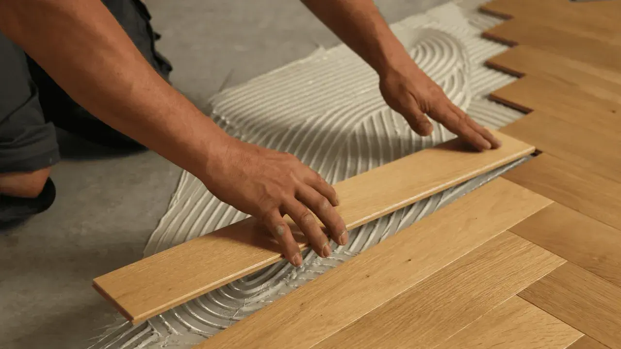 Man's hands carefully placing a wooden plank during the installation of floating flooring.