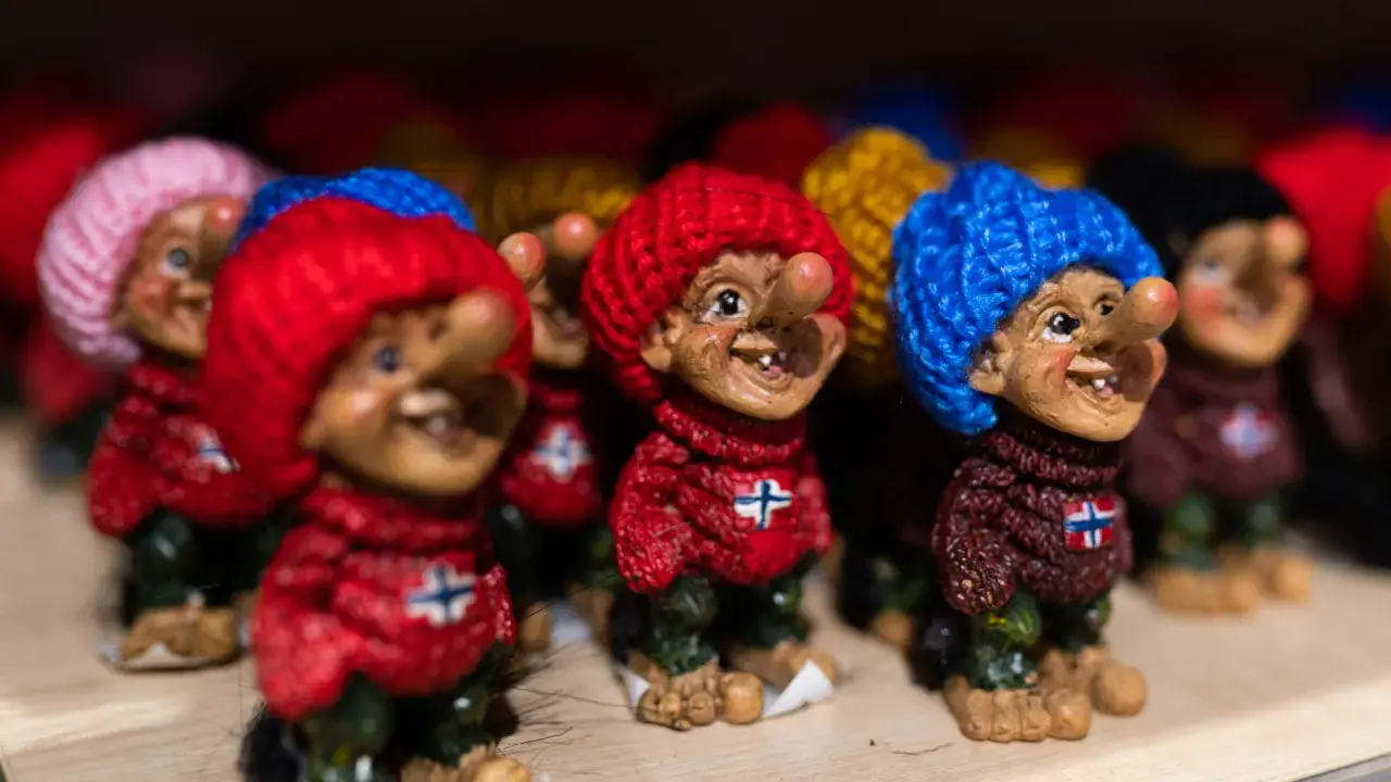 Uśmiechnięte trolle norweskie w kolorowych czapkach i sweterkach z norweską flagą.