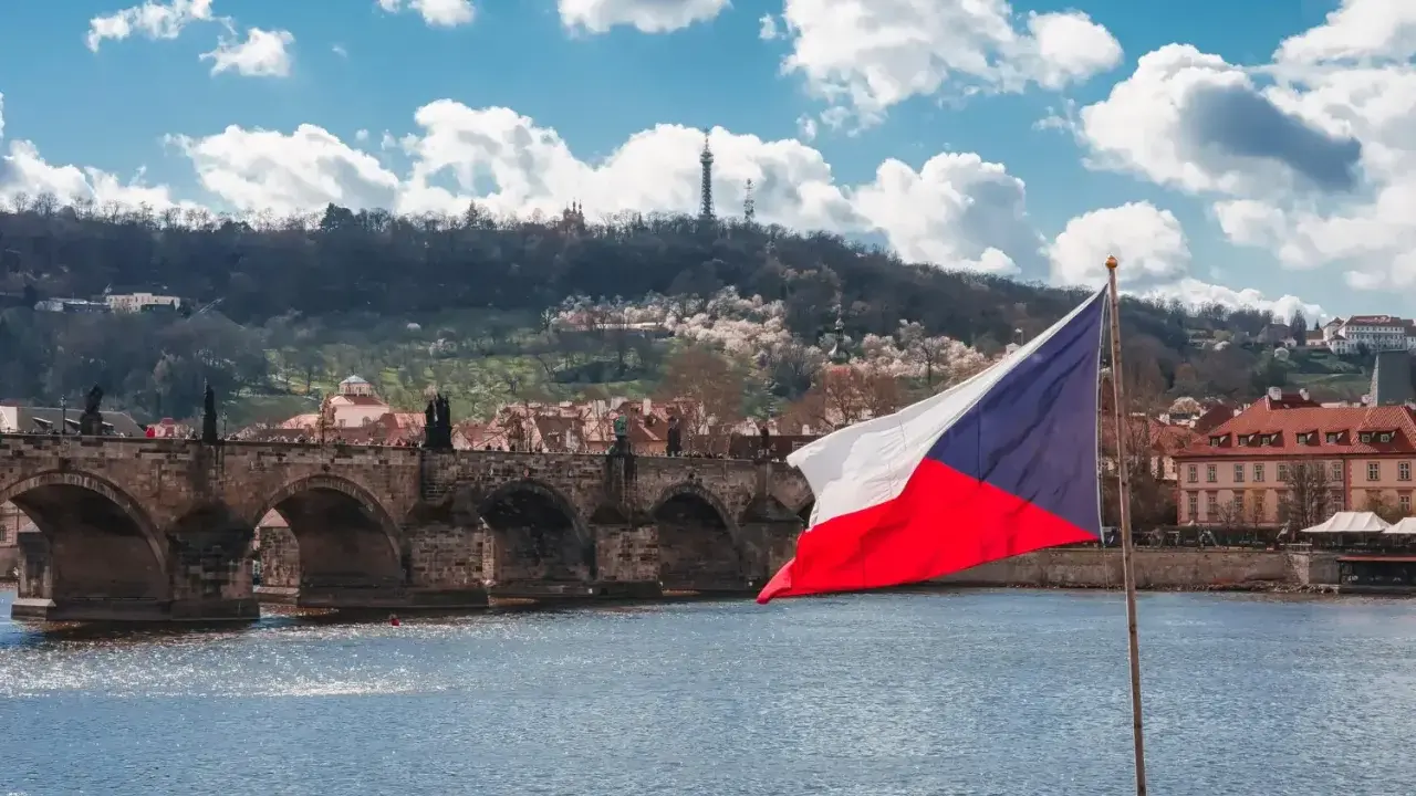 Flaga Czech na tle Mostu Karola w Pradze. Zastanawiasz się, ile idzie paczka z Czech do Polski?