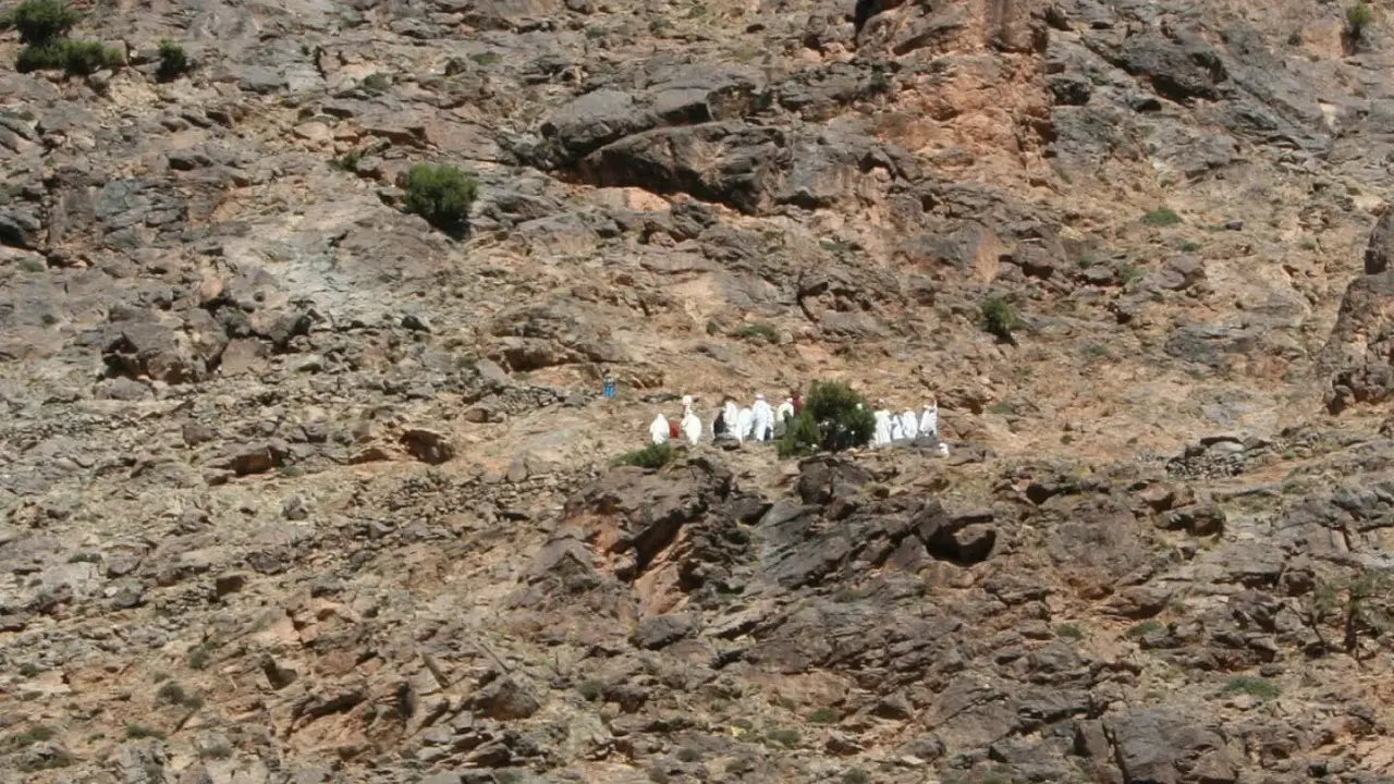 Eine Gruppe von Berber-Algeriern in traditioneller Kleidung wandert auf einem felsigen Hang.