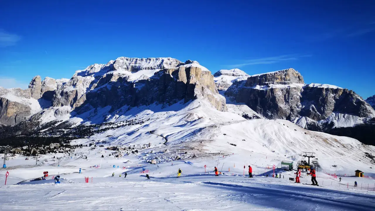 Piste innevate e maestose vette per decidere dove andare a sciare in Trentino. Sciatori e impianti di risalita animano il paesaggio.