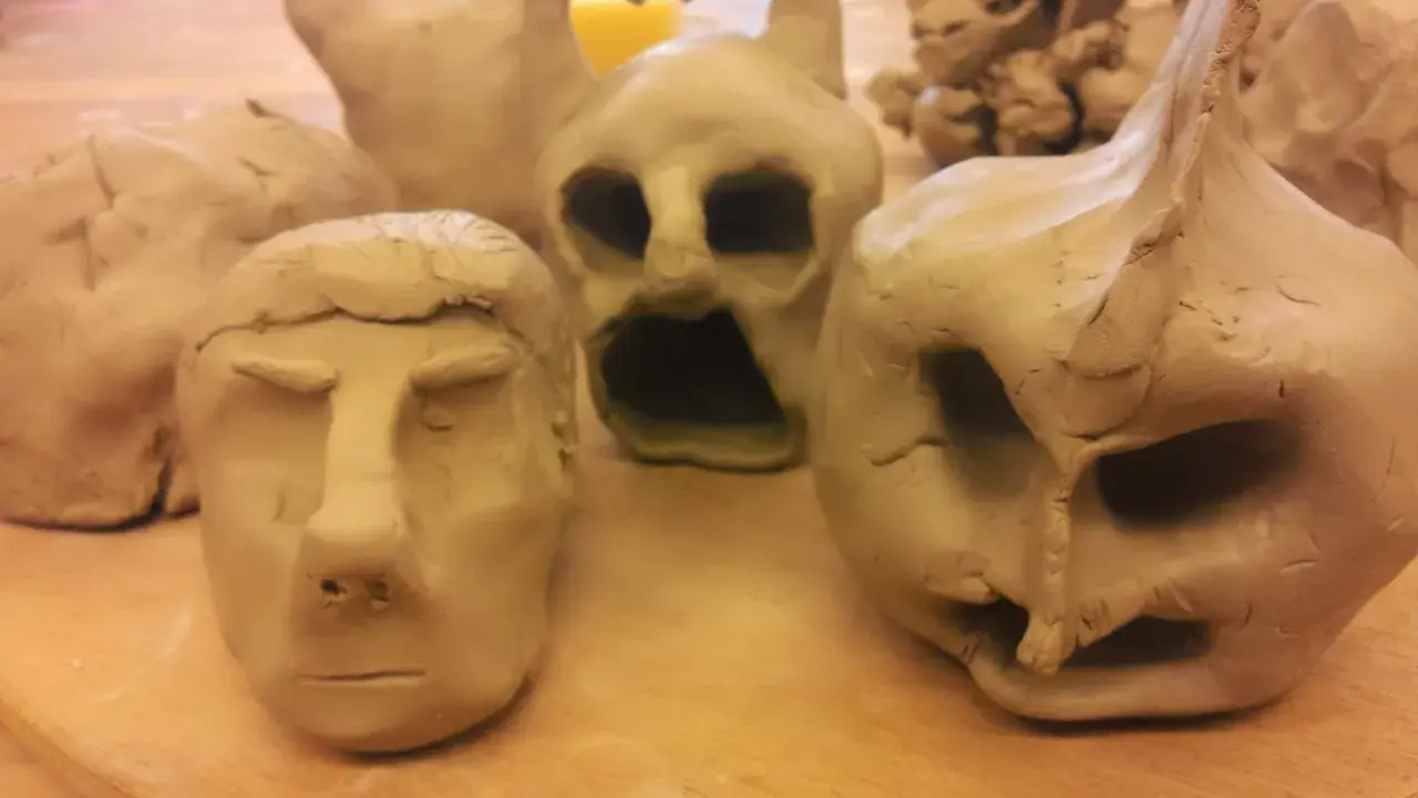 Flera ansikten och figurer i lera, skapade med fantasi. En del ser ut som monster, andra som människor.