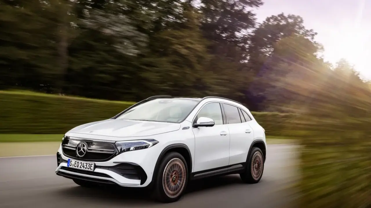 Un Mercedes EQA blanco circula por una carretera rodeada de árboles. Las **mercedes eqa medidas** son ideales para la ciudad y escapadas.