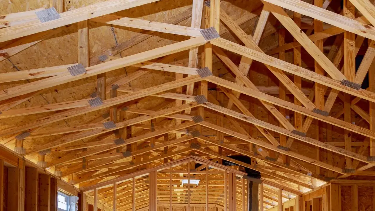 Structure complexe de charpente en bois, avec des fermes et des poutres formant un contreventement bois solide pour une nouvelle construction.
