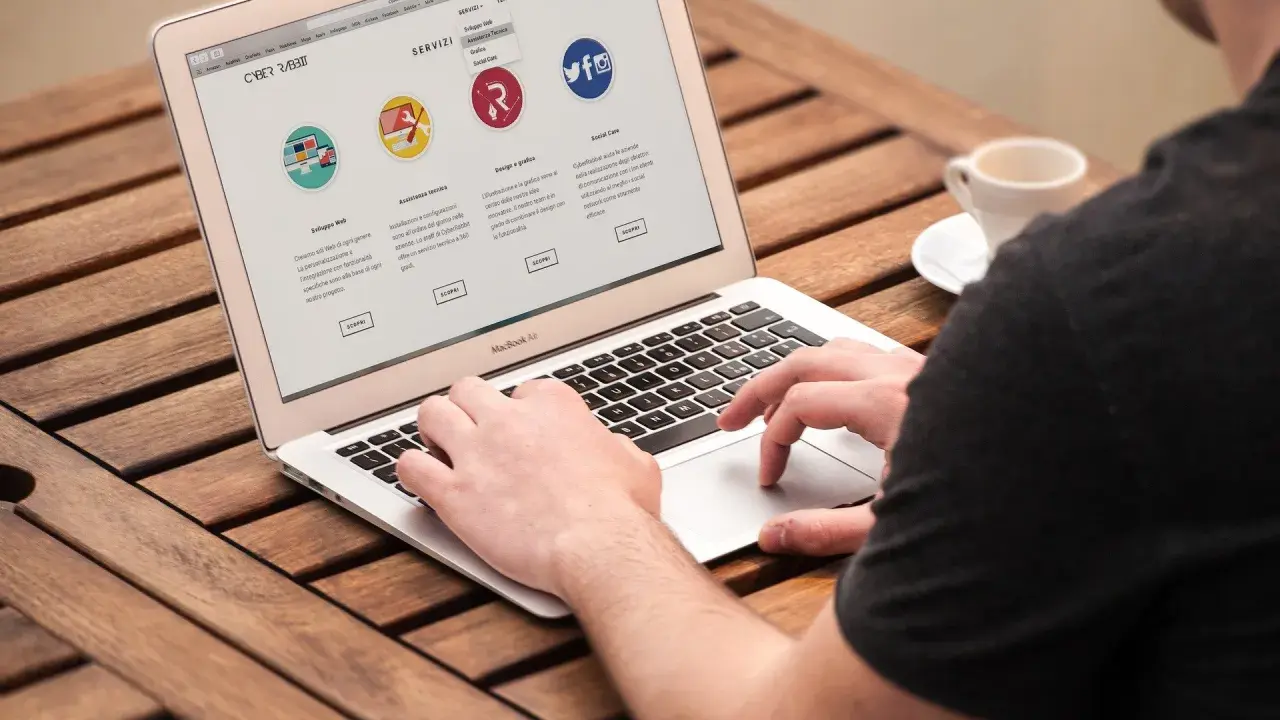 Mężczyzna pracuje na laptopie, przeglądając stronę internetową firmy CyberRabbit. Strona prezentuje usługi: rozwój stron, wsparcie techniczne, grafika i social media. To jest przykład, print co to jest.