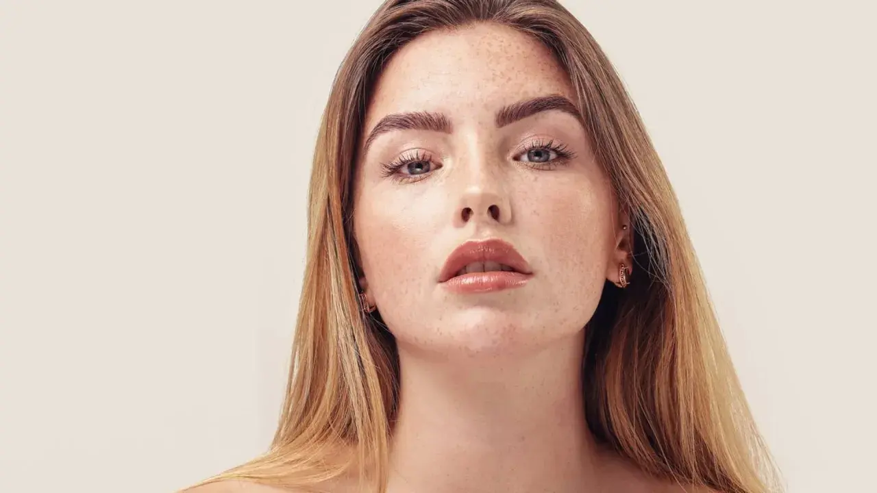 Nahaufnahme einer jungen Frau mit Sommersprossen und dunkelblond hellbraunen Haaren, die glänzend und glatt fallen.
