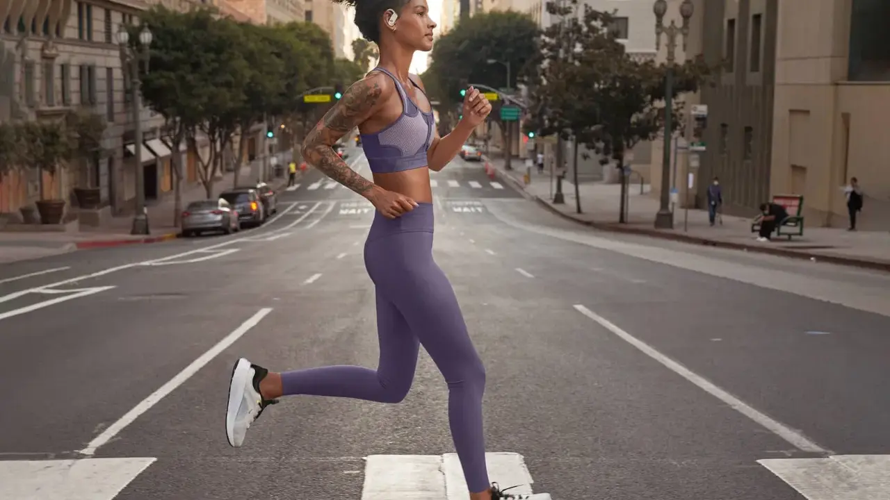 Donna in outfit viola, perfetto per come vestirsi in palestra, corre in strada.