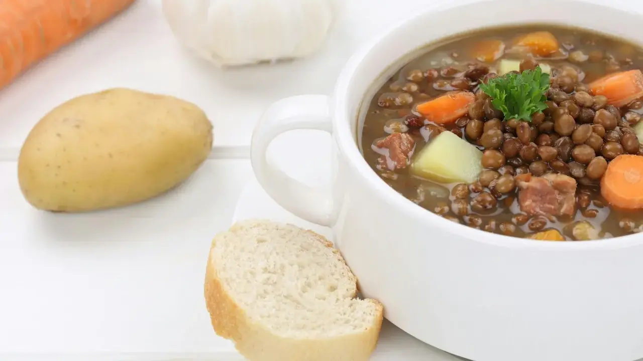Herzhafte Linsensuppe nach DDR-Rezept mit Kartoffeln, Karotten und Speck. Dazu ein Stück Brot.