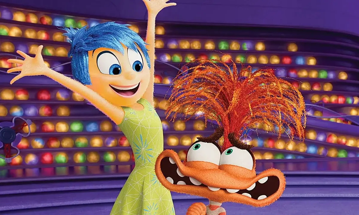 Alegría, del reves 2, salta feliz junto a un personaje naranja con pelo de fuego y ojos saltones, en un escenario de luces de colores.