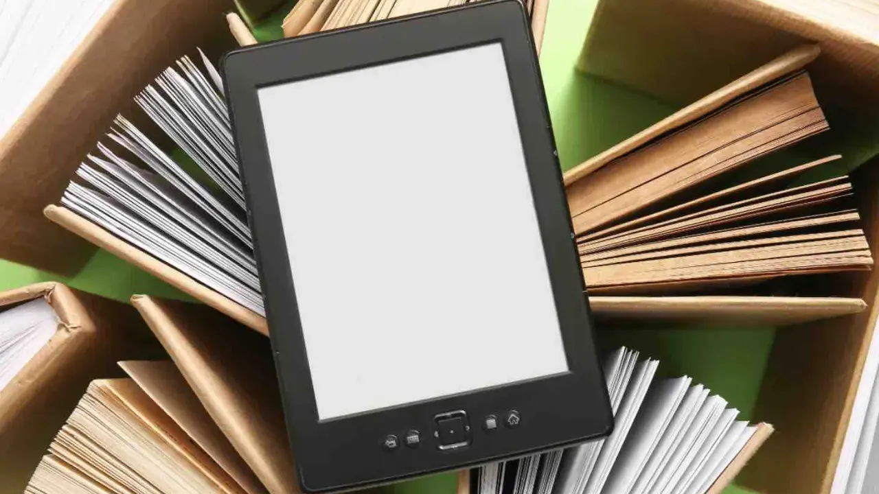 Un e-reader con schermo bianco è circondato da libri aperti, pronti per essere letti.