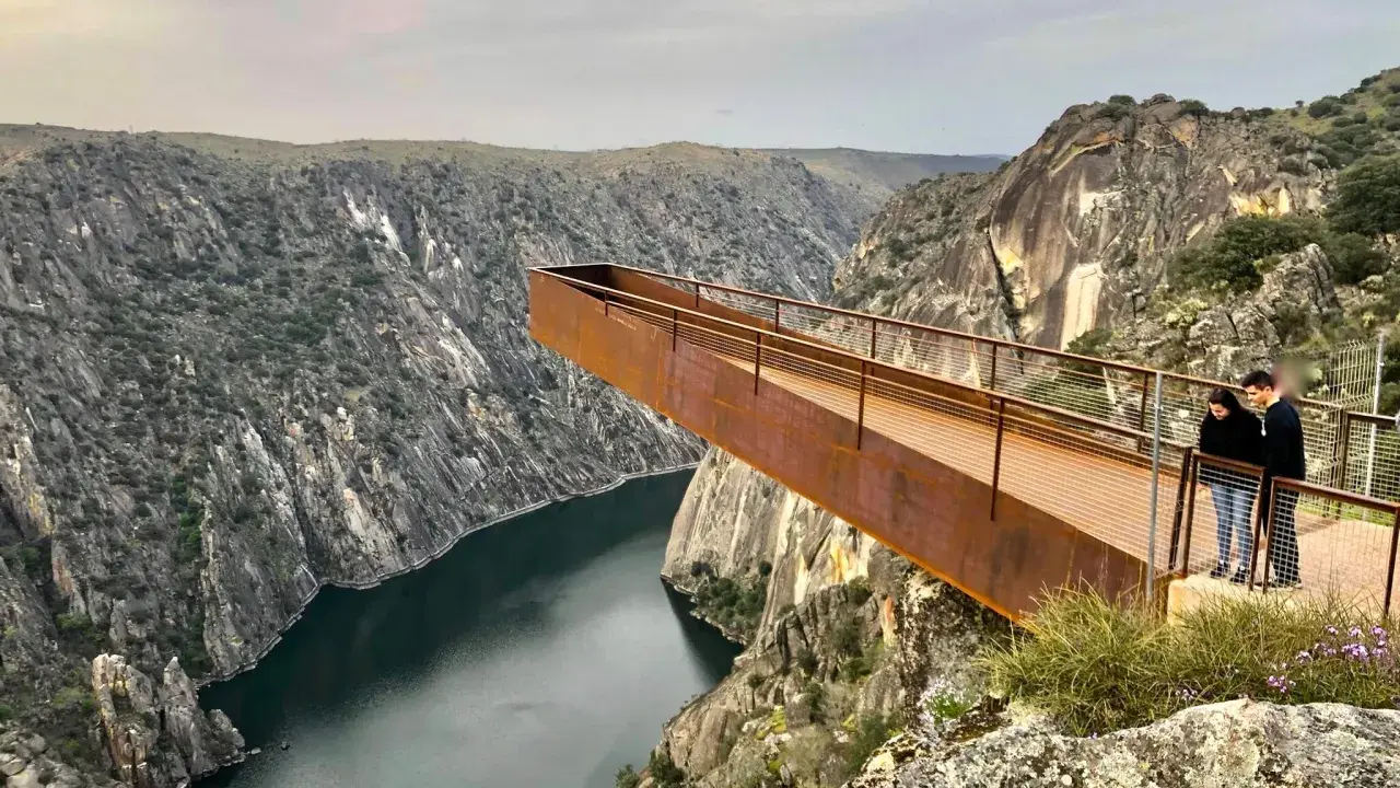 Pareja admira el paisaje desde el mirador del fraile, una pasarela metálica que se adentra en un cañón con un río.