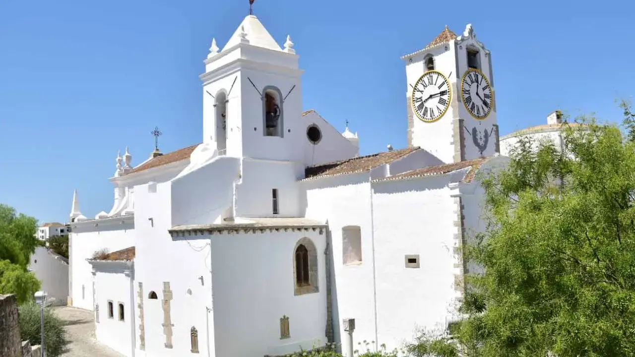 Weiße Kirche mit Glockenturm und Uhr im Herzen der tavira altstadt.