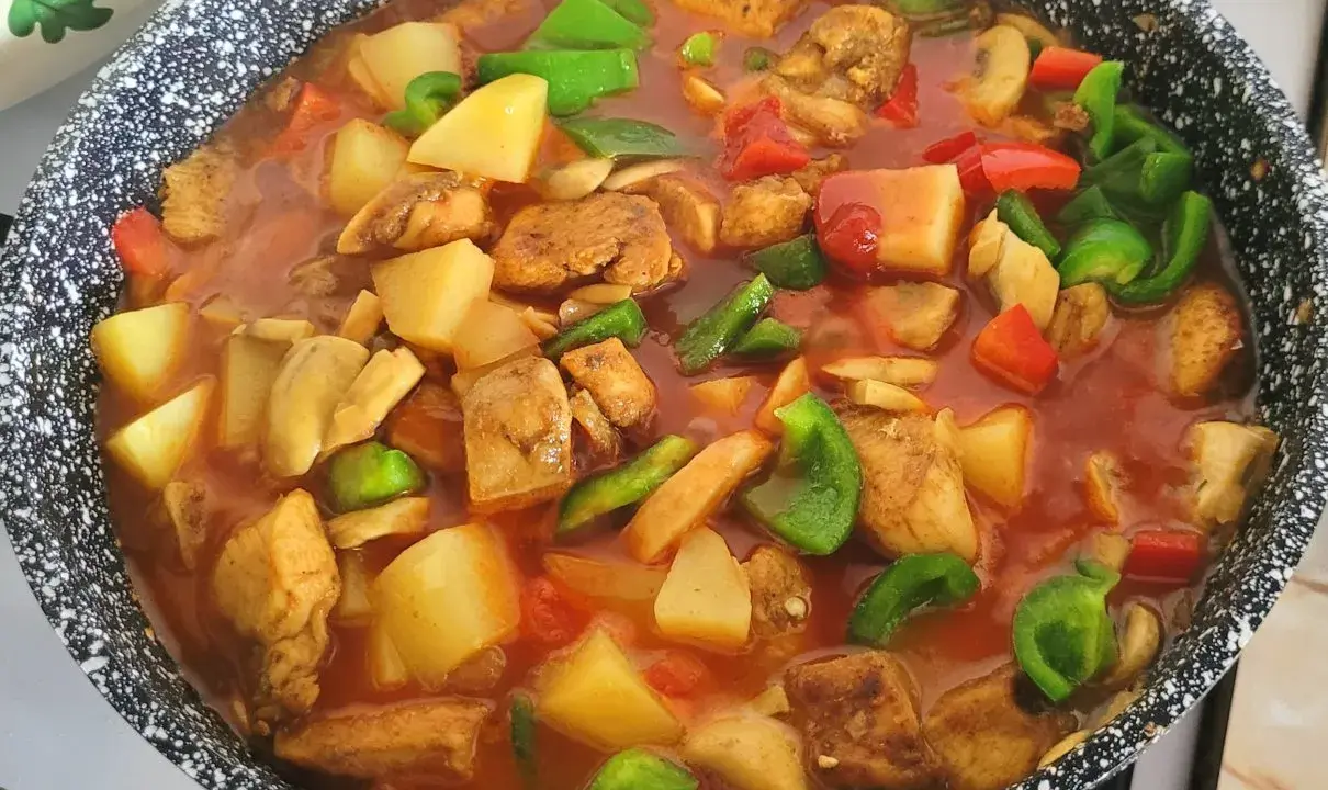 Gulasz z kurczaka w sosie pomidorowym z ziemniakami, papryką i pieczarkami, gotowy do podania.