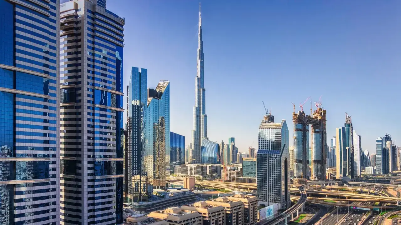 Nowoczesne wieżowce Dubaju, w tym Burj Khalifa, na tle błękitnego nieba. Widać autostrady i linie lotnicze Dubaj.