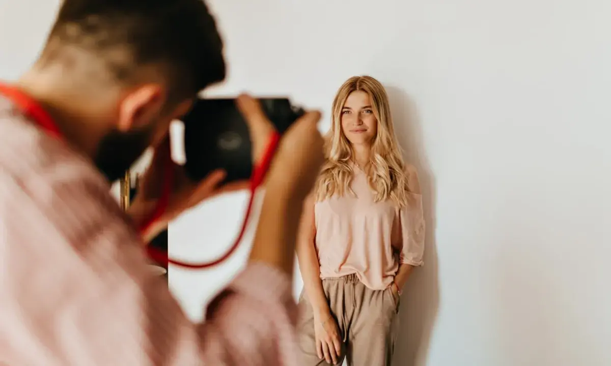 Fotograf robi zdjęcie uśmiechniętej blondynce. Zastanawiasz się, ile kosztuje sesja u fotografa?